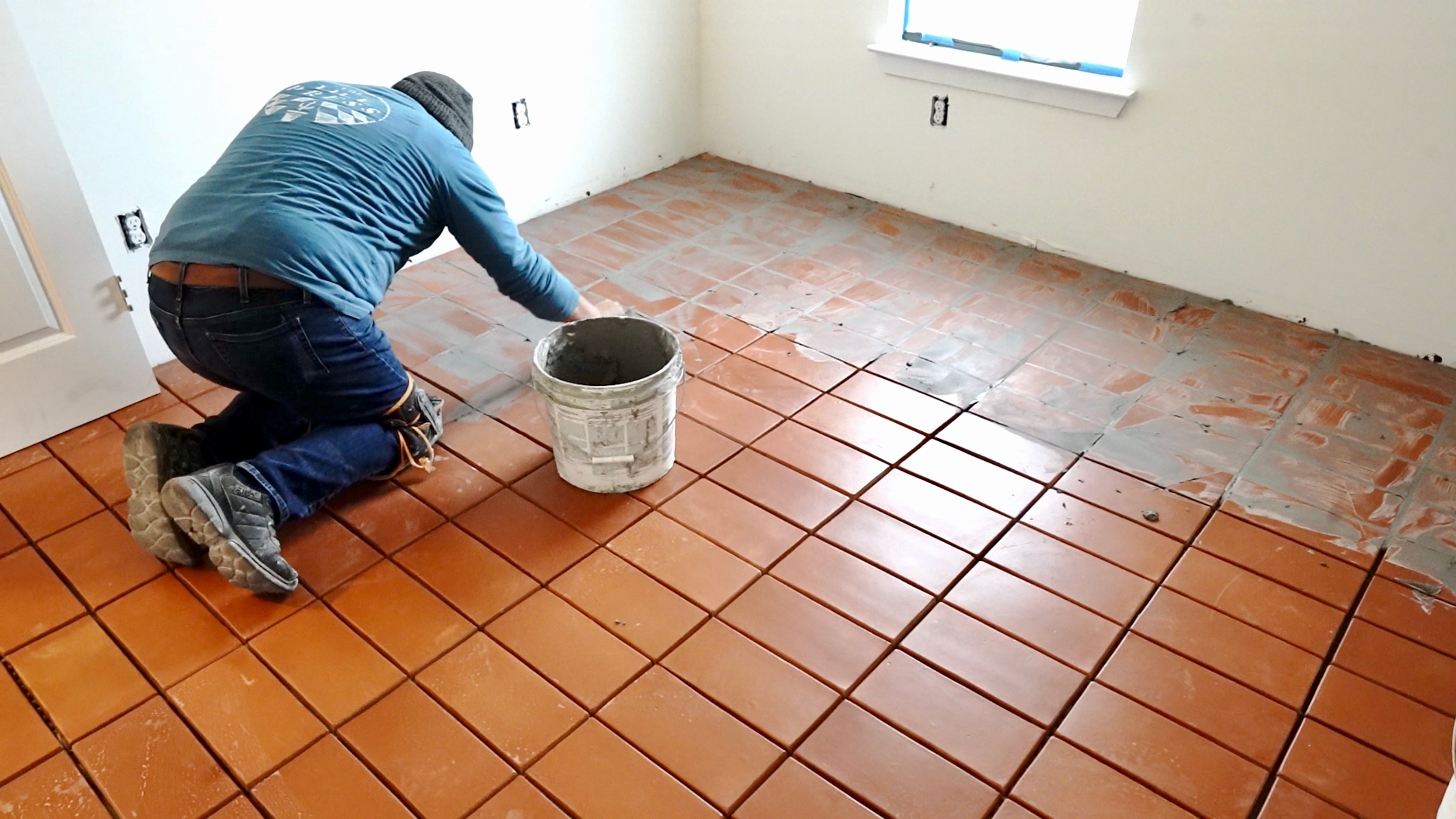 Tile worker grouting red terracotta clay tiles inside a house clay imports