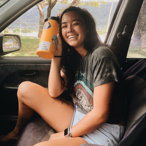 Picture of Kaitlyn holding her mango colored water bottle with the HULA sticker on it