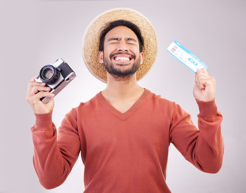 happy man holding camera and ticket in hands