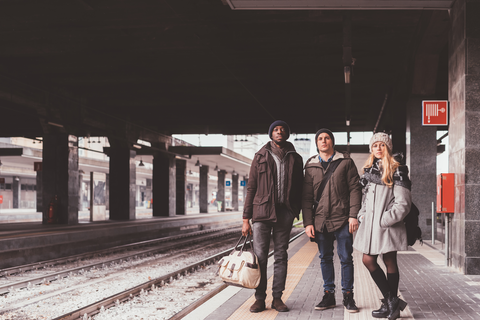 travellers standing on train platform with luggage