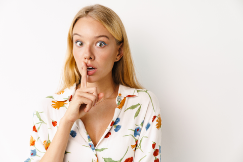 potrait of woman with finger on lips hiding a secret