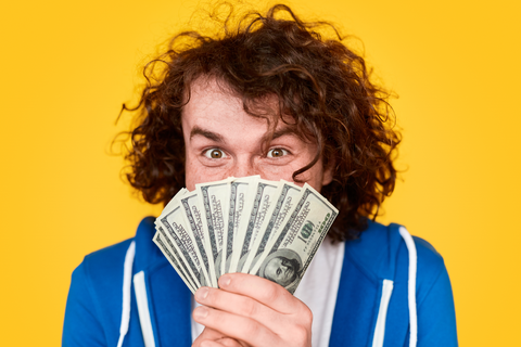 excited man holding money in front of his face