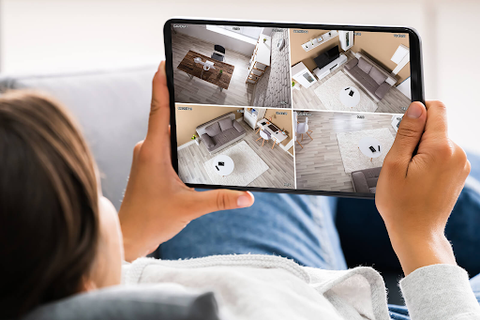 A lady is watching your house from a tablet connected to her surveillance cameras