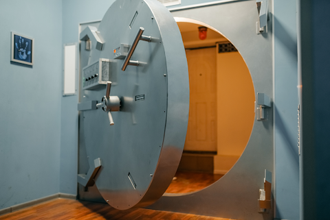A huge safe with a big circular steel door with locks on the front