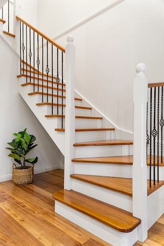 some wooden stairs with a white banister in a hall painted white