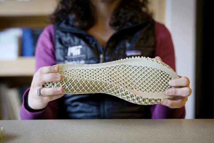 A model developed by MIT engineers predicts the optimal running shoe design for a given runner. Pictured is a researcher holding a 3-D-printed midsole, designed based on the model’s predictions. Credits: Melanie Gonick, MIT