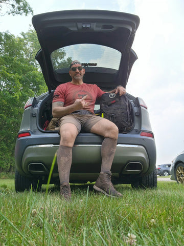 MudGear Athlete Lou Greco relaxes in the trunk of his car post-race in mud-crusted gear.