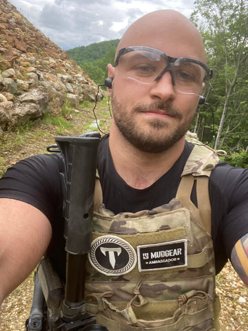 Determined athlete Zack Wisnowski treks down a trail in a vest bearing MudGear patches.
