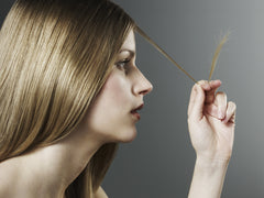woman looking at her hair strand