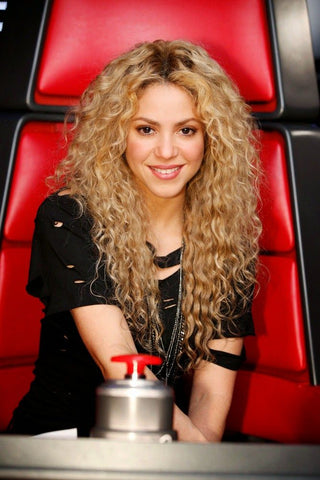 Shakira with curly hair sitting in the voice chair