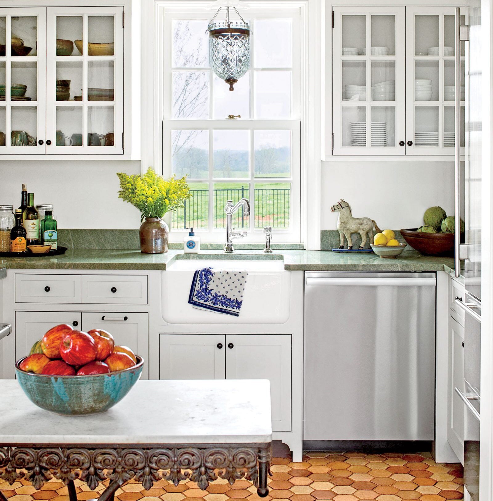 Kitchen with White Cabinets Green Countertop Terra Cotta Floor Kitchen Sink with Window next to Brushed Stainless Steel Magnet Skin on Dishwasher with White Control Panels