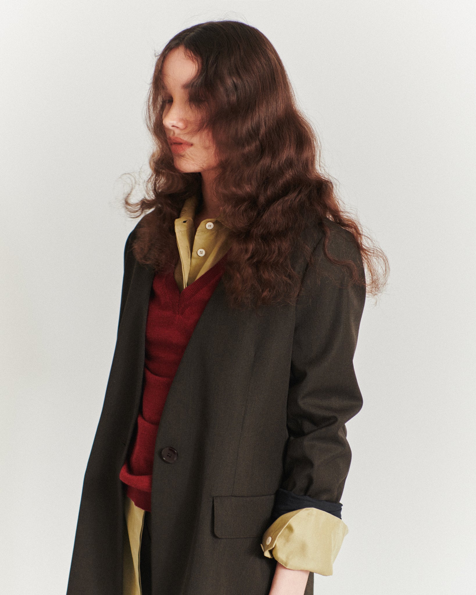 detail of model wearing an Issue Twelve green shirt, red jumper and brown wool blazer