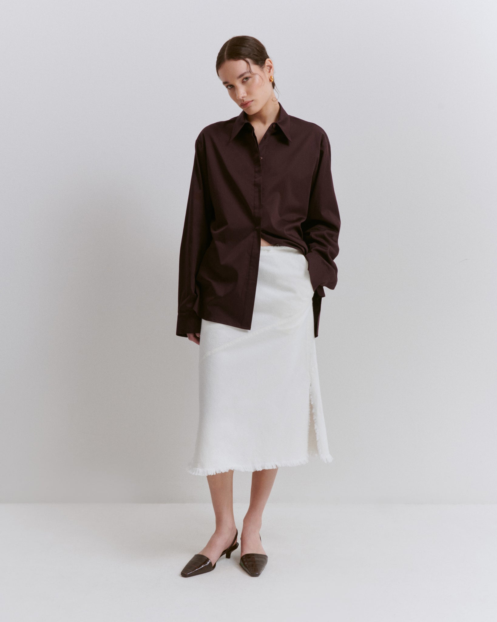 model wears Issue Twelve aubergine shirt in cotton with an organic cotton white denim skirt