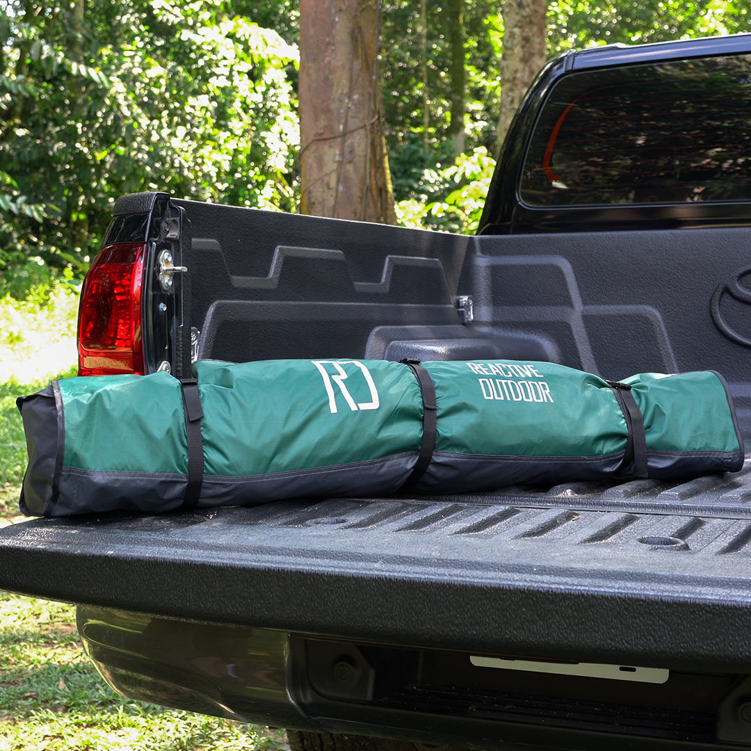 A green tent bag labeled 'Readyone Outdoor' on the bed of a black pickup truck.