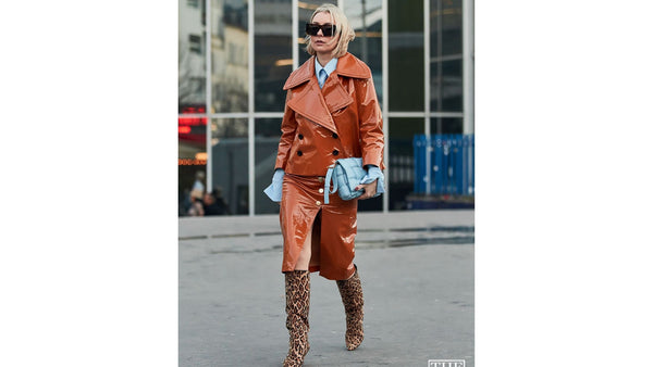 skiim-girl-wears-double-patent-leather-oranged-jacket-and-skirt-and-leopard-skiim-knee-high-boots-and-holds-pale-blue-clutch