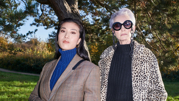 two-models-wearing-skiim-outfits-outside-in-a-park-one-woman-wears-skiim-blue-cashmere-jumper-and-a-check-blazer-and-one-woman-wears-black-cashmere-jumper-large-sunglasses-and-leopard-coat