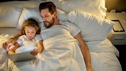 un père et sa fille regardant un écran de téléphone avant d'aller au lit