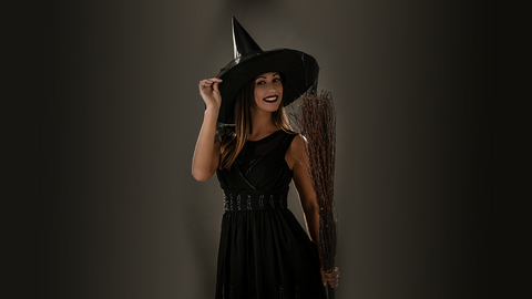 une dame habillée en sorcière porte un balai de sorcière pour Halloween