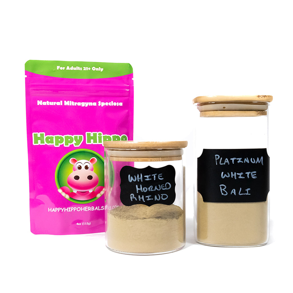 Photographic image depicting a packet of Happy Hippo brand, white vein kratom powder, in front of which are two glass jars. The first jar contains white vein horned (white rhino) kratom powder, and the second jar contains White Vein Bali (Platinum White Bali) kratom powder