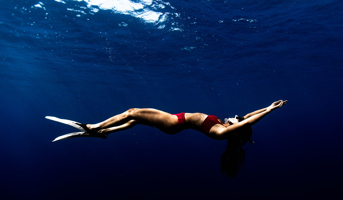 Marie floating underwater wearing Dkoko's sustainable surf bikinis