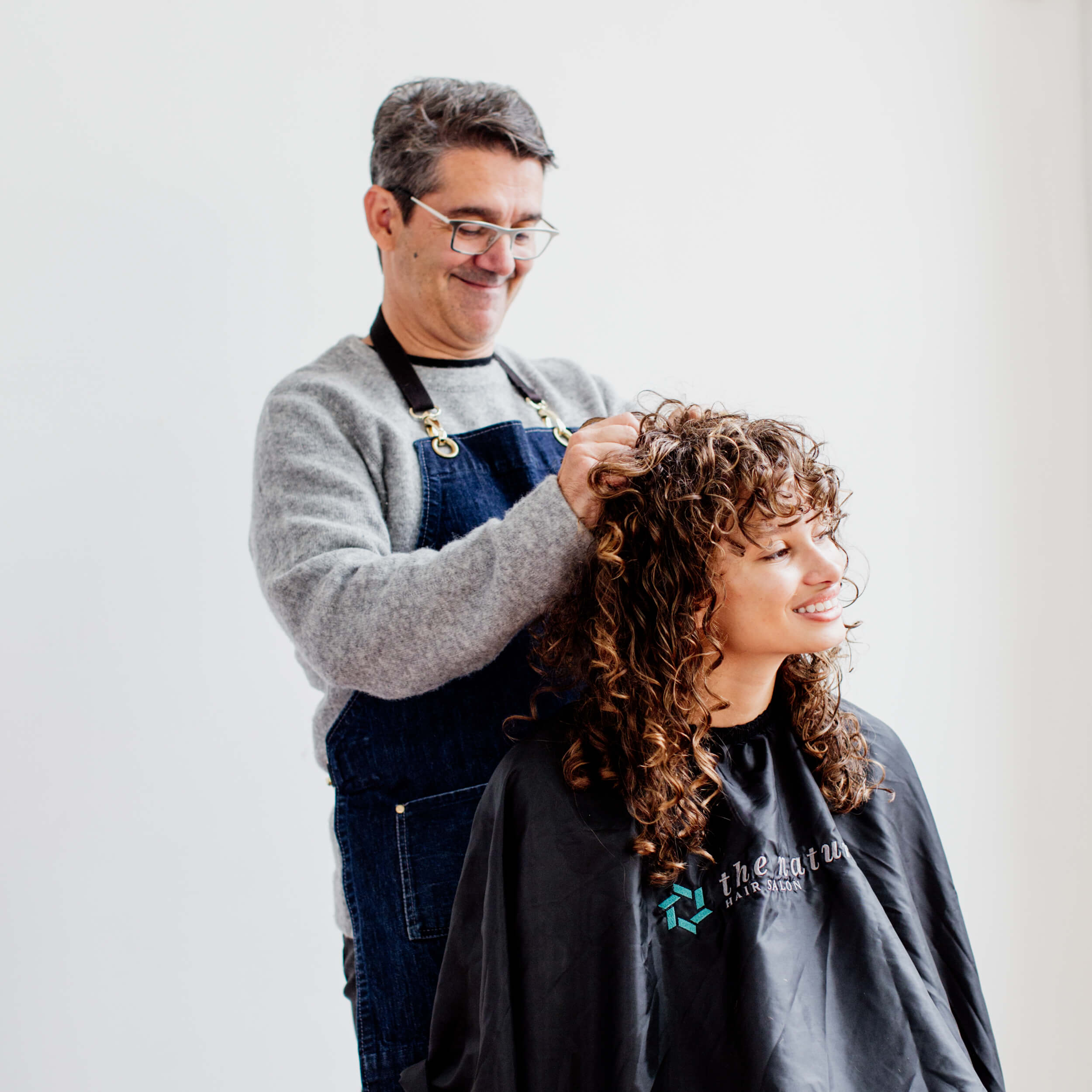 A hairdresser works on a client's hair.