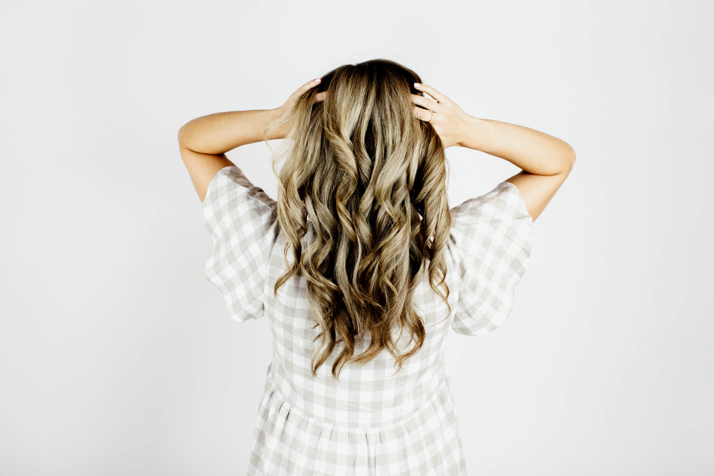 A head of curly blonde hair seen from the back.