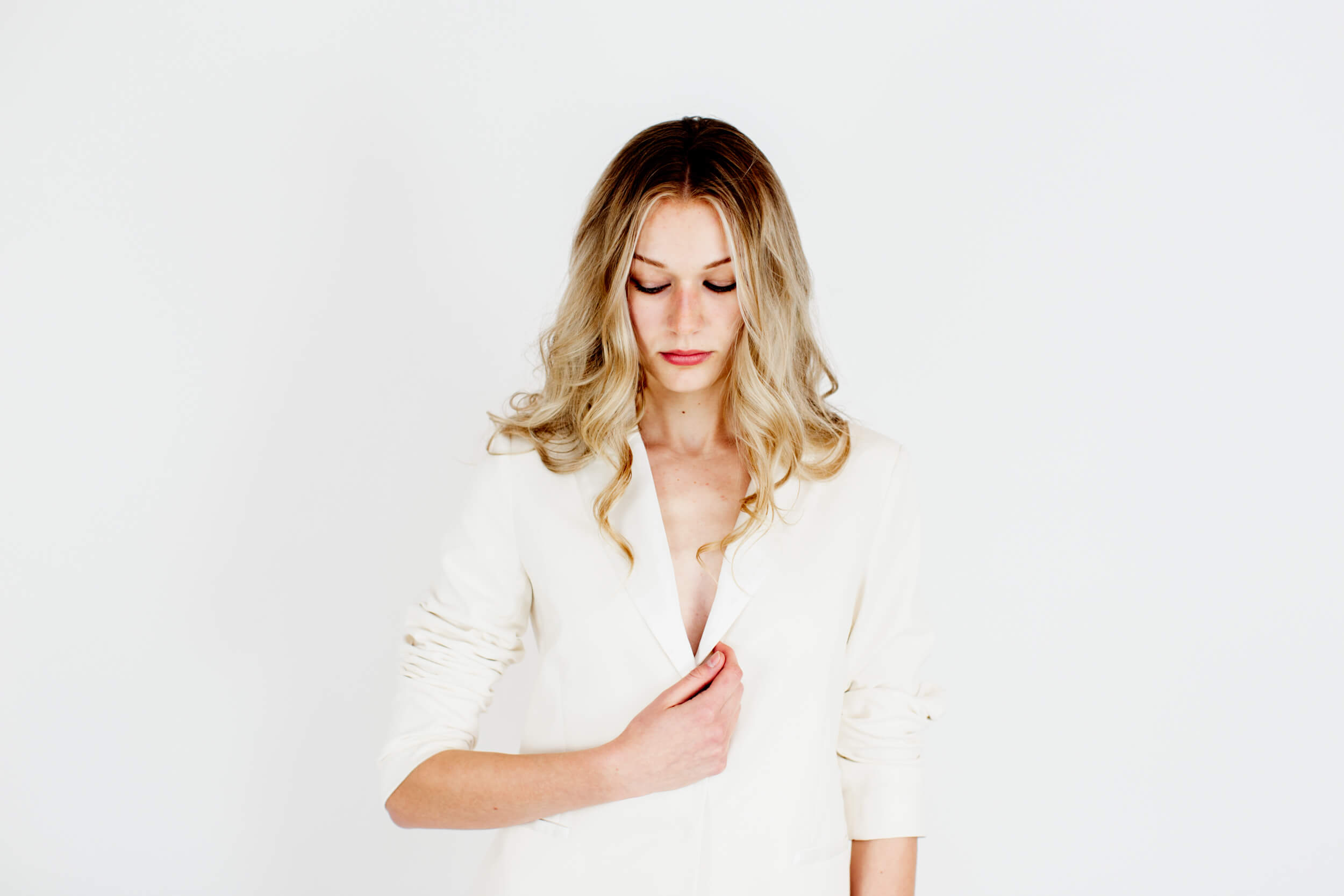 A woman in a white suit poses for the camera.