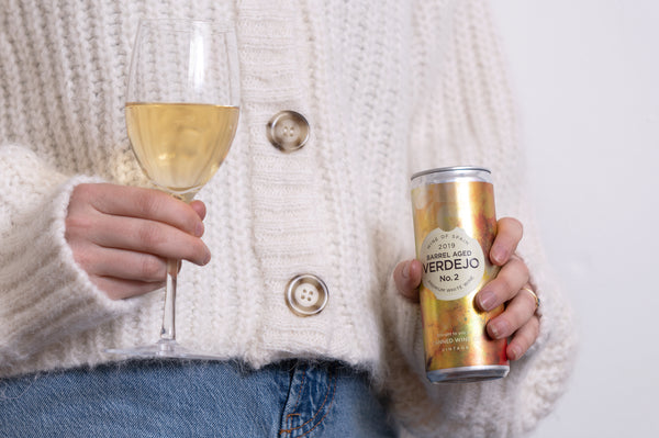 Woman holding a Canned Wine Co. Barrel Aged Verdejo and a white wine glass