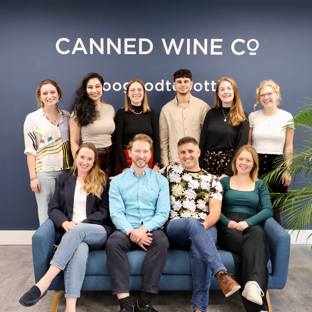 Canned Wine Co. team photo in front of branded logo wall