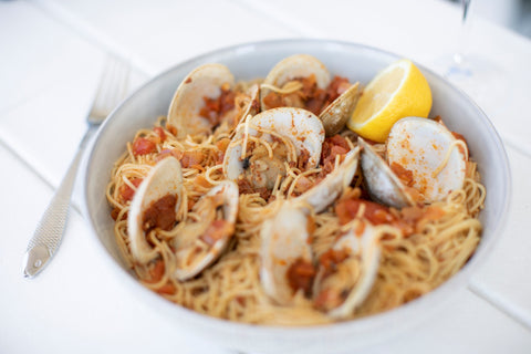 angel hair pasta with red sauce and steamed clams, lemon wedge on the side