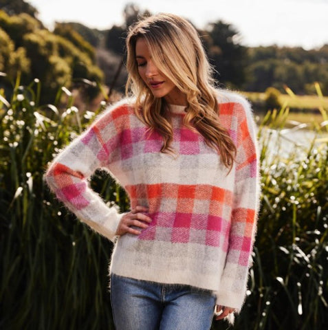 Woman wearing angora pink and orange check sweater and blue jeans.