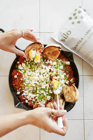 a brightly coloured image of shakshuka, taken from above with a package of Silo large green lentils in the upper right corner