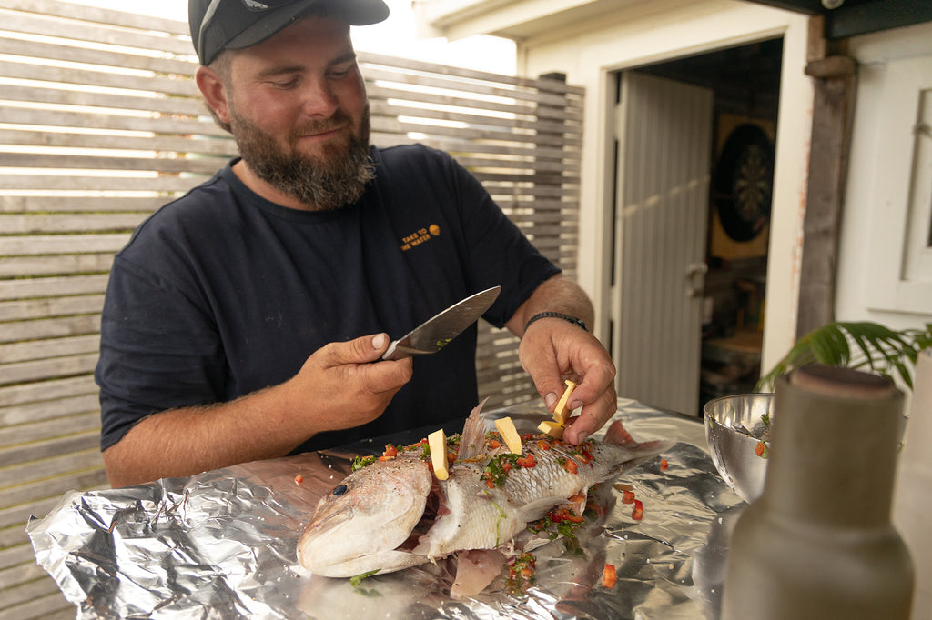 Greeny prepping the whole cooked snapper - Wearing the Desolve Classic TTTW Tee - Navy