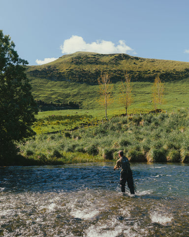 Henry fishing for trout in the rapids, wearing the Trutta Tee in Khaki and the Drift Wader.