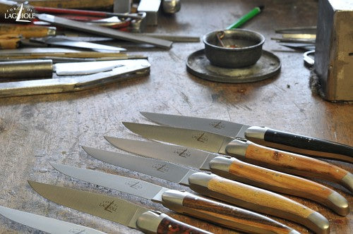 several forge de laguiole steak knives on a work bench at the shop
