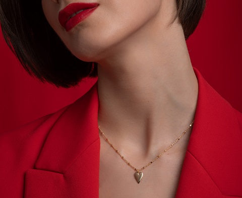 njo designs gold heart drop necklace on model wearing red
