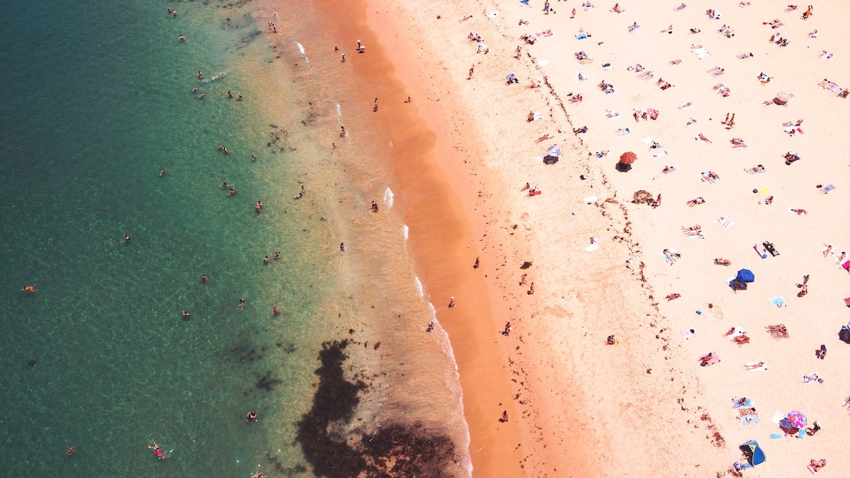 arial view of the blue ocean, shoreline and people scattered on Coogee Beach, Australia
