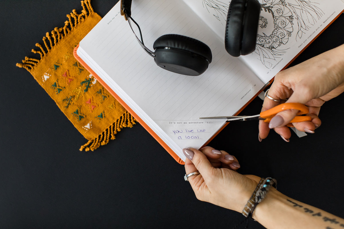 someone cutting a journal prompt out of a mindful travel journal