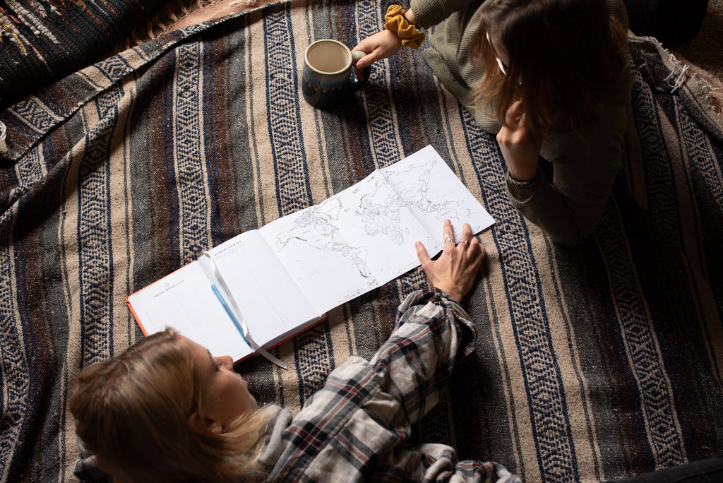 two girls laying looking at the fold out map in the wakeful travel journal