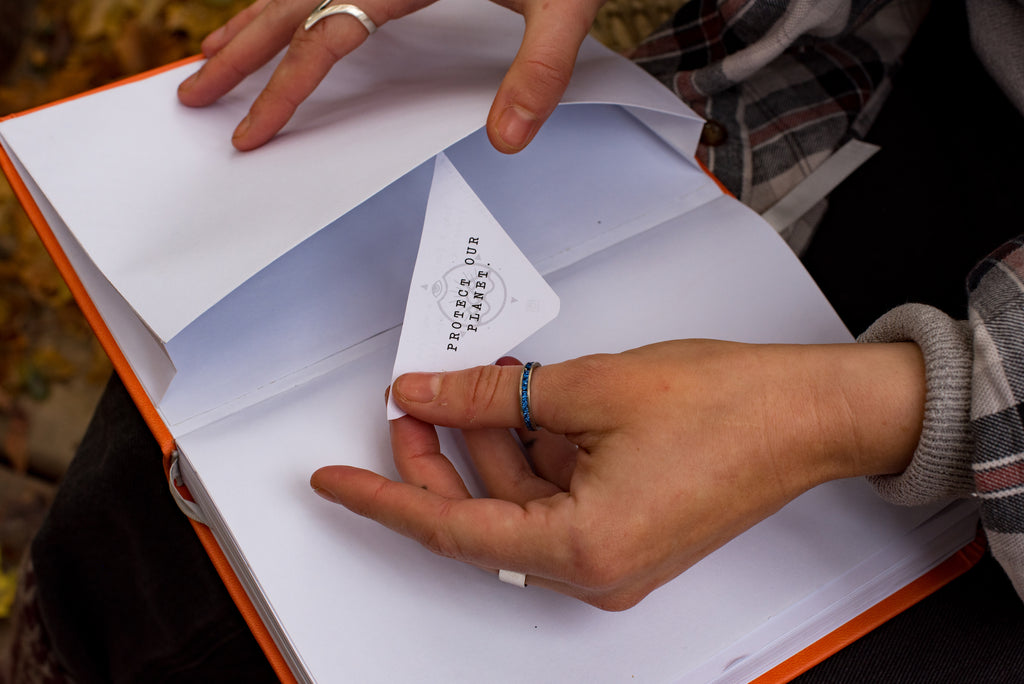 close up of girl putting piece of paper in the back pocket of the journal