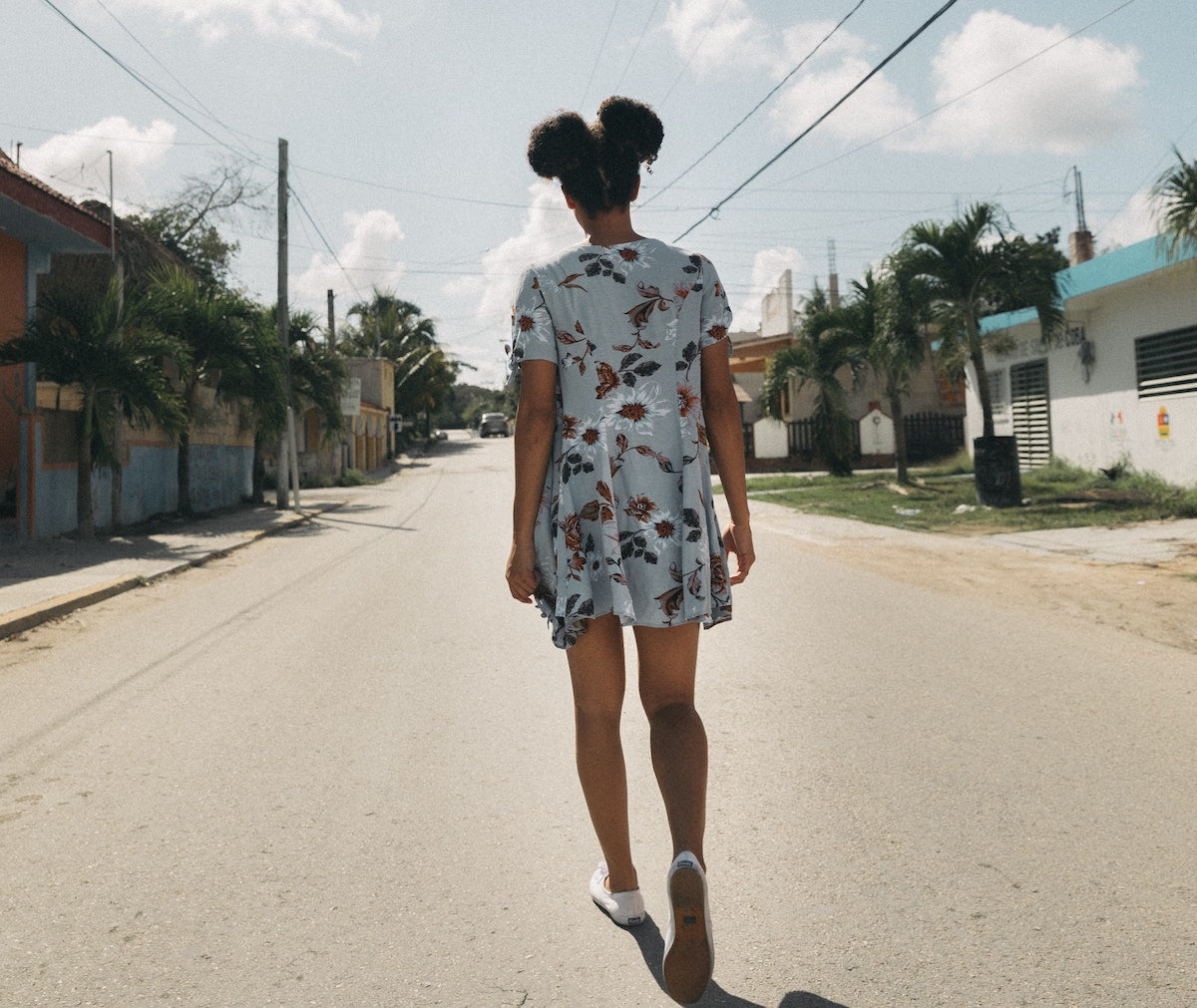 an African American girl in a dress walking down the street