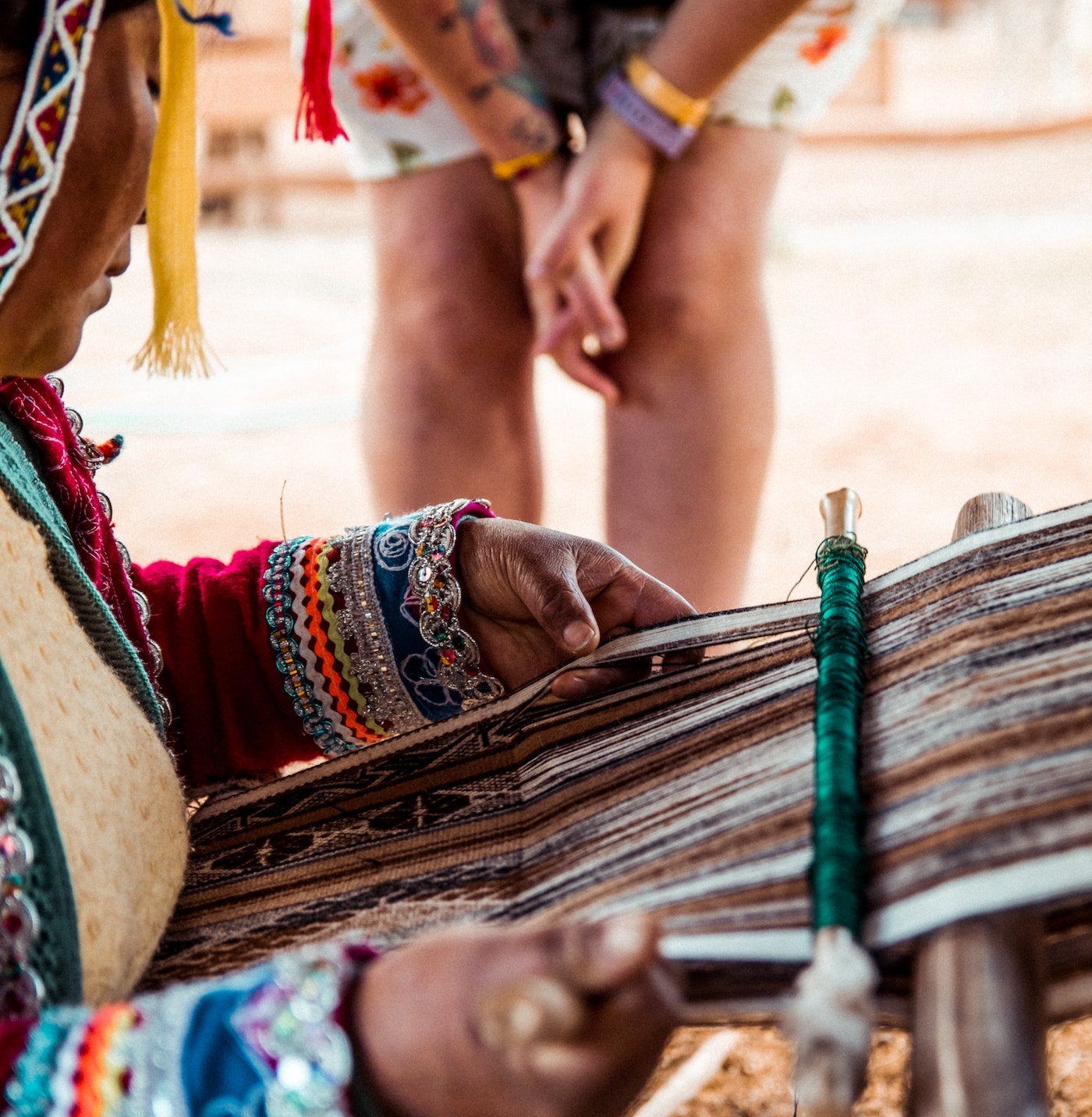 peruvian woman weaving while a tourist watches closely