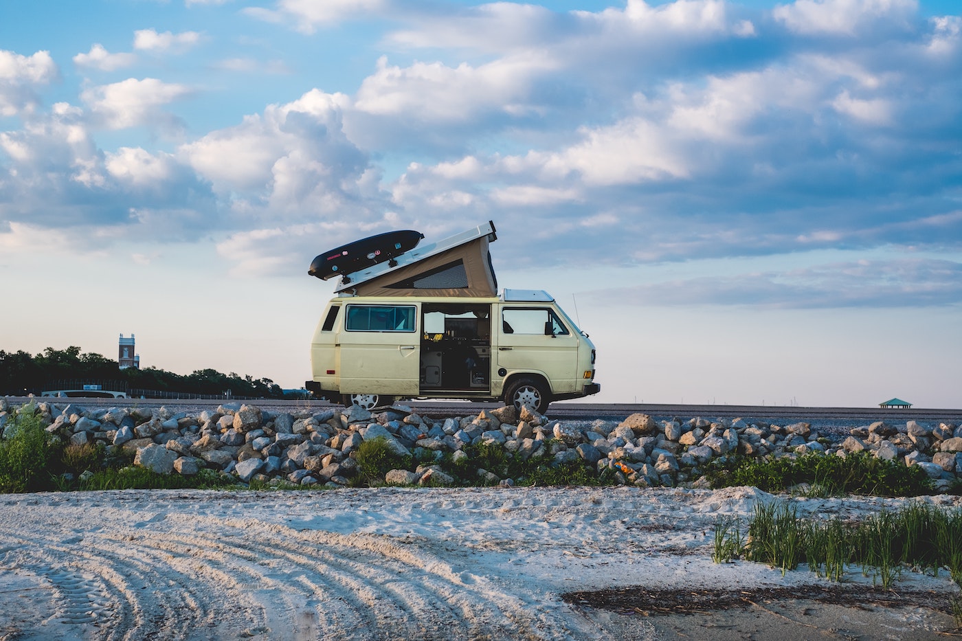 a pop-top van on a rocky beach with blue sky