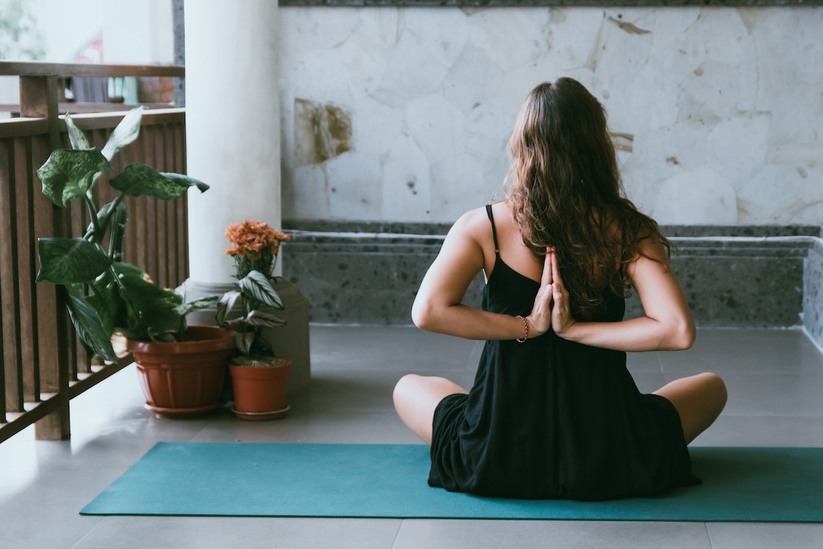 Woman sitting in easy pose with hands behind her back in prayer