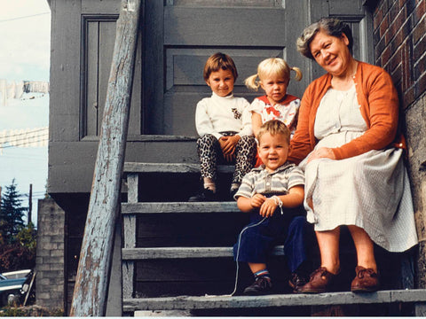 A woman and her three grandchildren sitting on stairs outside her townhouse in a moment of togetherness and happiness. 