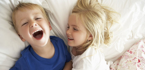Lachende Kinder im Kinderbett