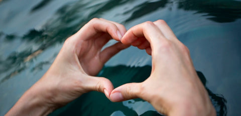 Hands form heart over water