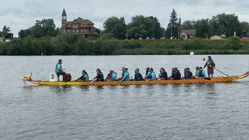 Team members of Loll Designs in a dragon boat in the bay of Barker's Island. They are rowing for the Dragon Boats Festival in Superior, WI.