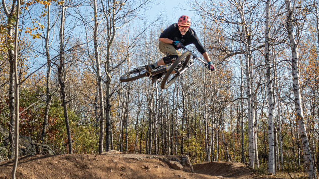 Image: Man in the air on a mountain bike trail riding a mountain bike.