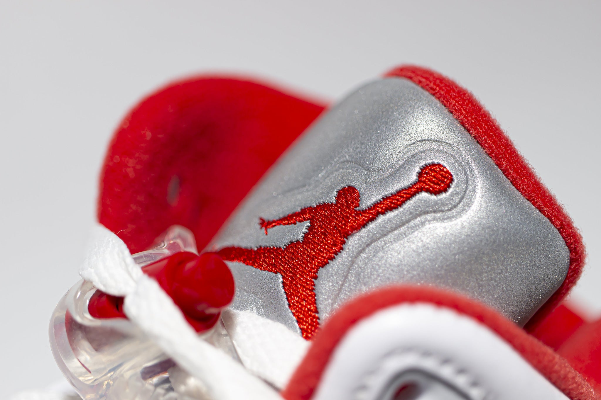 Close up view of embroidered red jumpman logo on 3m reflective sneaker tongue